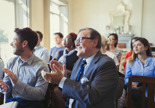 Smiling business people clapping in business conference audience