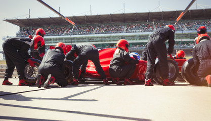 Pit crew replacing tires on formula one race car in pit lane