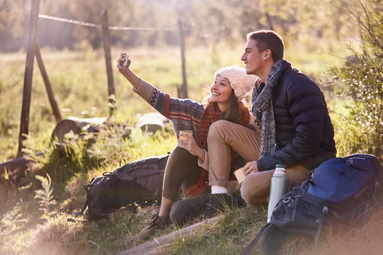 Young couple taking a break from hiking, taking selfie camera phone