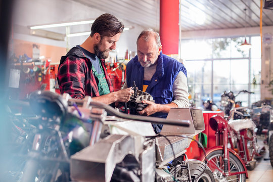 Male motorcycle mechanics repairing part in workshop