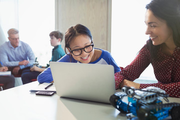 Female teacher girl student programming robotics at laptop in classroom