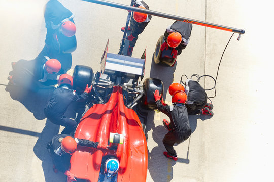 Overhead Pit Crew Replacing Tires On Formula One Race Car In Pit Lane