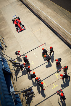 Pit crew ready for nearing formula one race car in pit lane