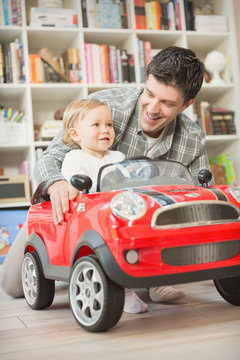 Father pushing baby son in toy car