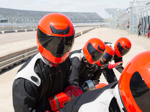 Pit crew wearing helmets in sunny pit lane