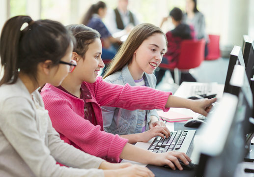 Girl students studying together at computer in library