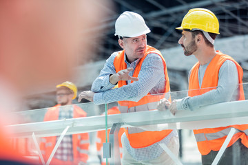 Male foreman and construction worker talking at construction site