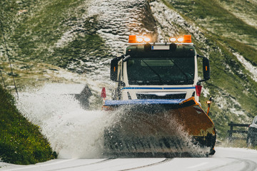 Frontal picture of a truck with a plough cleaning heavy fresh snow on a mountain pass of...