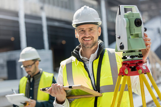 Portrait smiling male engineer using theodolite at construction site