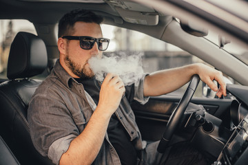 Young handsome man smoke with vape in vehicle