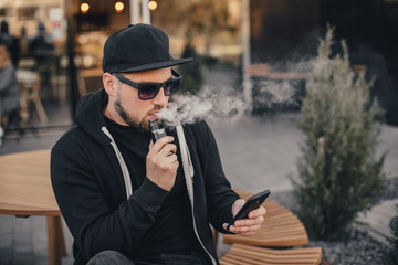 Young handsome man smoke with vape in urban location