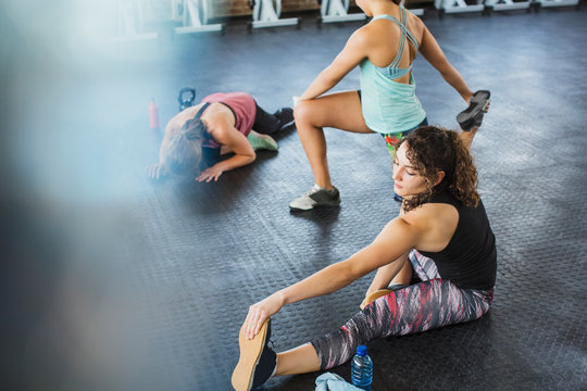 Young women stretching legs in gym
