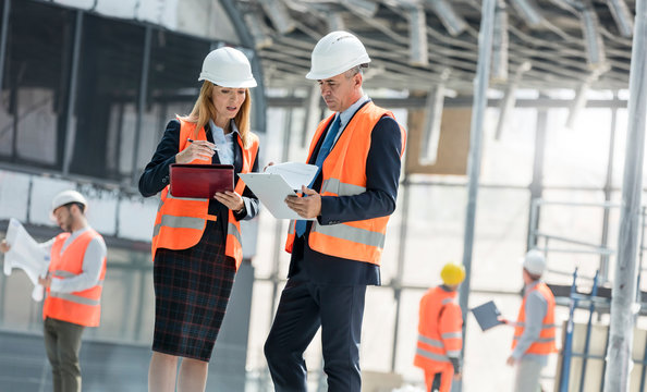 Engineers with clipboards meeting at construction site