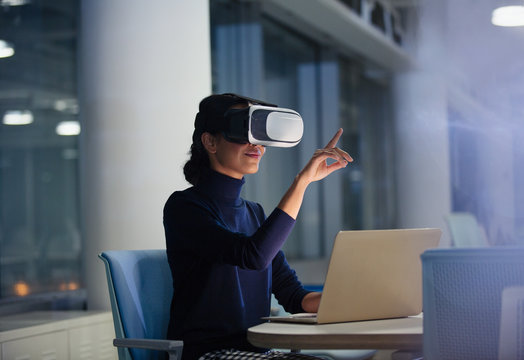 Businesswoman using virtual reality simulator at laptop in office