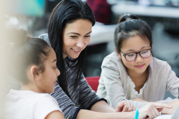 Female teacher and girl students using laptop in classroom