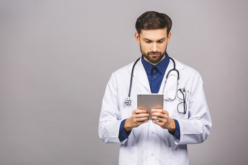 Smiling doctor using a tablet computer isolated on a grey background.