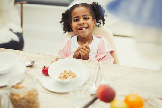 Portrait smiling girl eating breakfast at table