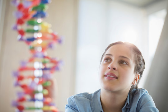 Pensive girl students examining DNA model in classroom laboratory