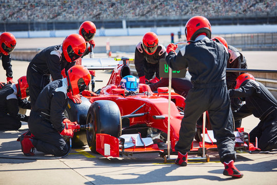 Pit crew working on formula one race car in pit lane