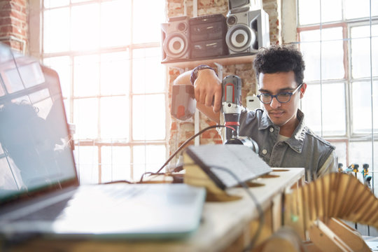 Male designer using power drill in workshop