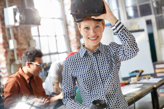 Portrait smiling female computer programmer wearing virtual reality simulator glasses