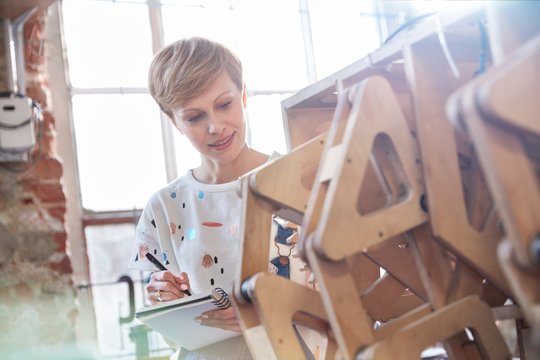 Female designer examining prototype and taking notes