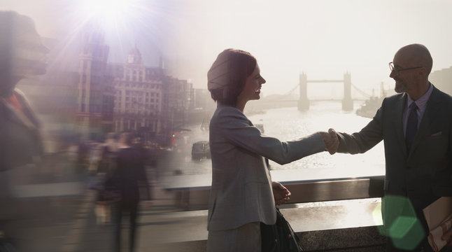 Silhouette business people handshaking on sunny bridge over River Thames, London, UK