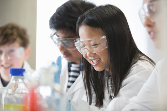 Smiling girl conducting scientific experiment in laboratory classroom
