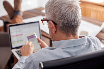 Businessman working, using cell phone and laptop in office