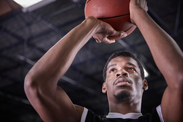 Focused young male basketball player shooting free throw