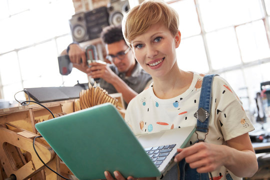 Portrait smiling female designer using laptop in workshop