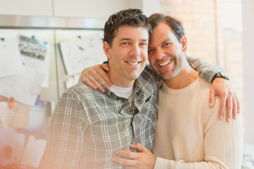 Portrait smiling, affectionate male gay couple hugging in kitchen