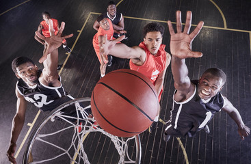 Overhead view young male basketball players jumping to rebound basketball at net on basketball court