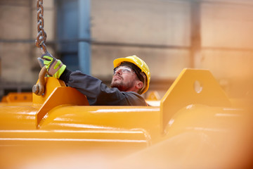 Male worker attaching chain to equipment in factory