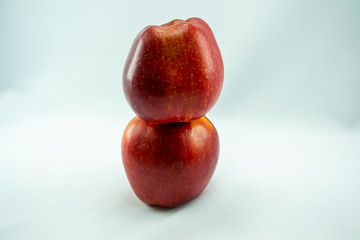 two red apples one standing on the other, white background