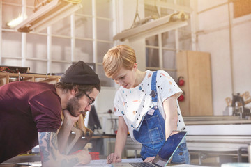 Designers reviewing plans at laptop in workshop