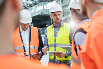 Male foreman, engineers construction workers meeting at construction site
