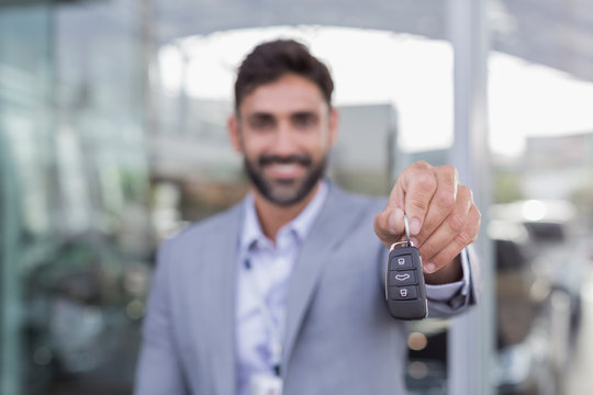 Portrait smiling, confident car salesman holding, showing new car keys