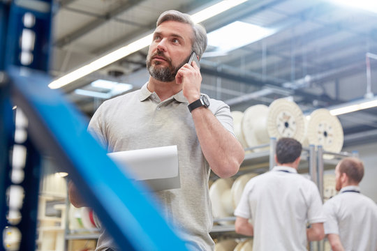 Male supervisor clipboard talking on cell phone in fiber optics factory