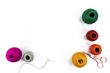 Embroidery accessories. Multicolored bundles of thread, scissors, sewing needles. White background...