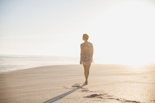 Pensive, serene woman walking on sunny summer beach