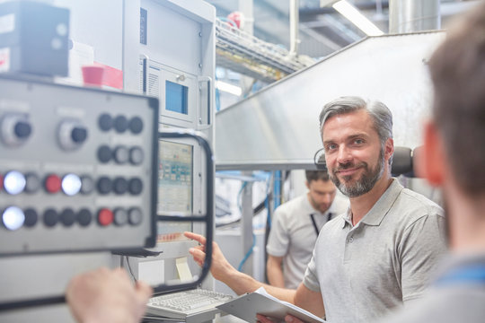 Portrait smiling male manager at machinery control panel in factory