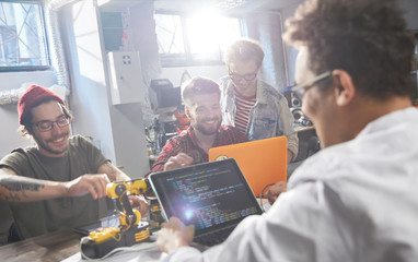 Computer programmers programming robotics in workshop