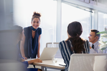 Businesswoman at laptop leading conference room meeting