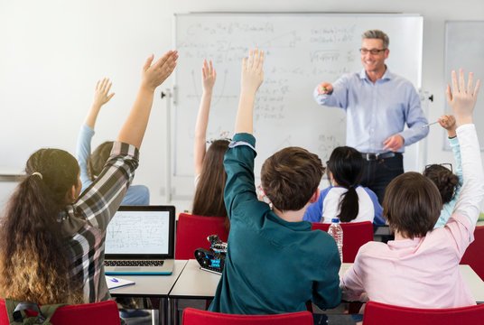 Male teacher calling on students in classroom