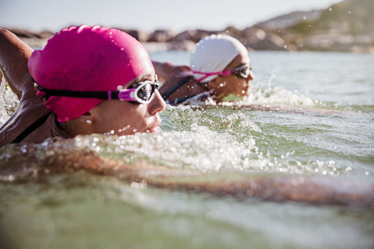 Female open water swimmers swimming in sunny ocean