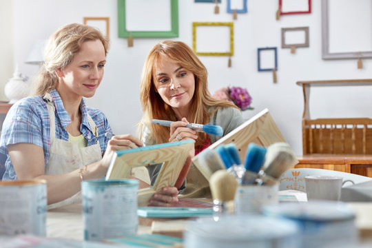 Female artists painting picture frames in art class workshop