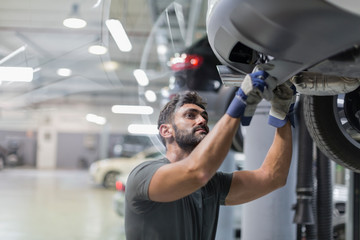 Male mechanic working under car in auto repair shop