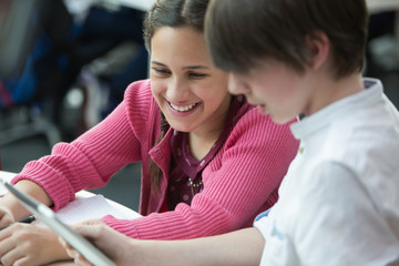 Smiling students using digital tablet in classroom