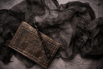 Old book with spells and magic wand on gray background with witch rag. Copy space for text